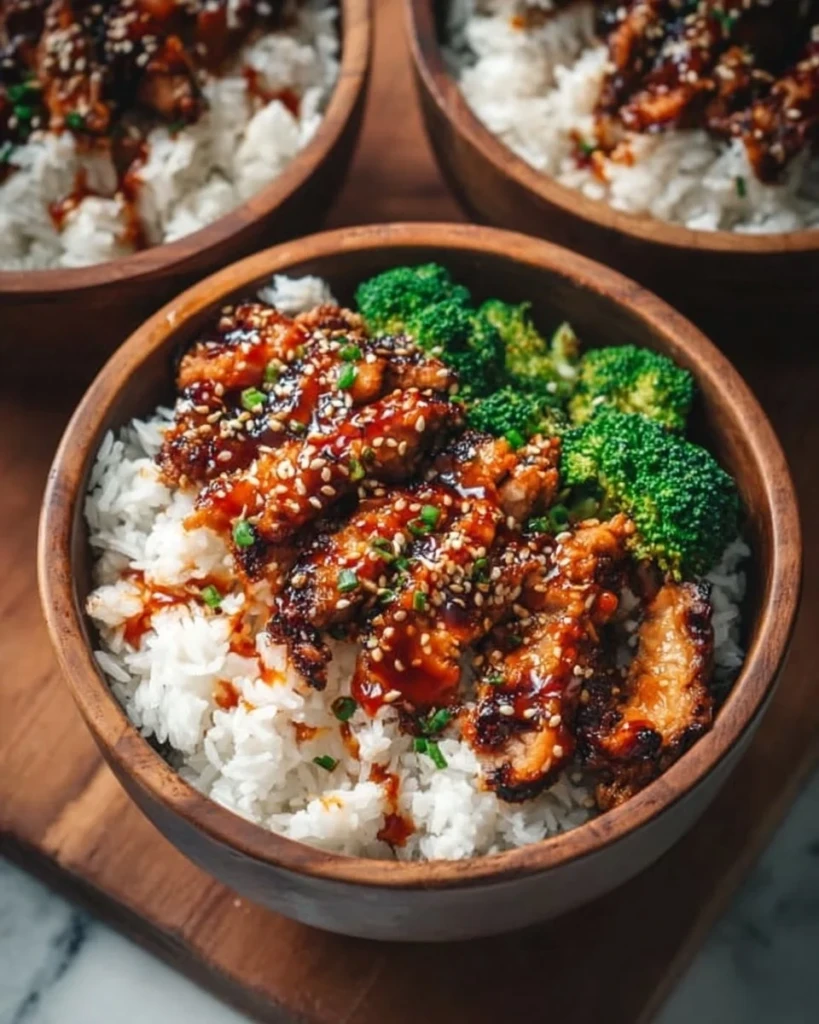 Delicious sticky chicken rice bowl garnished with herbs and vegetables