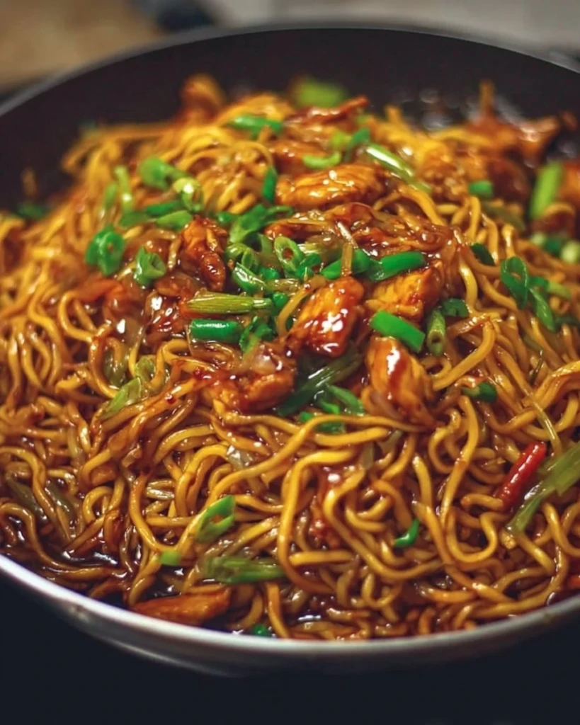 Plate of sticky garlic chicken noodles garnished with green onions