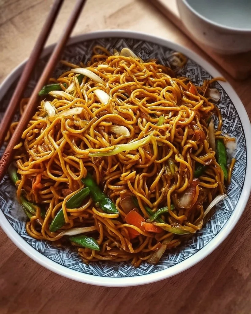 Plate of classic Chinese fried noodles garnished with vegetables and spices