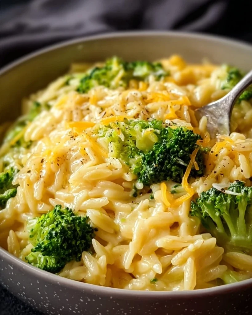 Creamy one-pot broccoli cheddar orzo dish served in a bowl with fresh broccoli