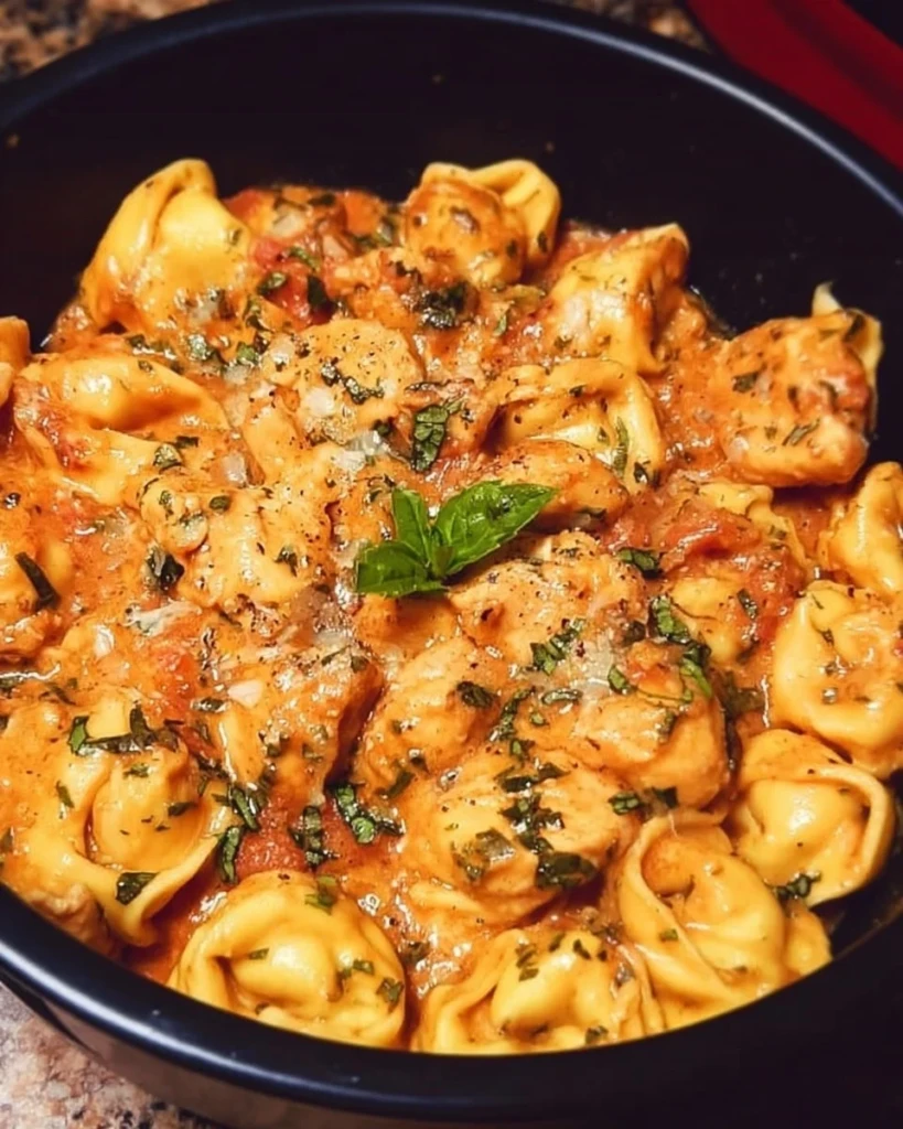 Delicious CrockPot Chicken Tortellini recipe served in a bowl with fresh herbs.