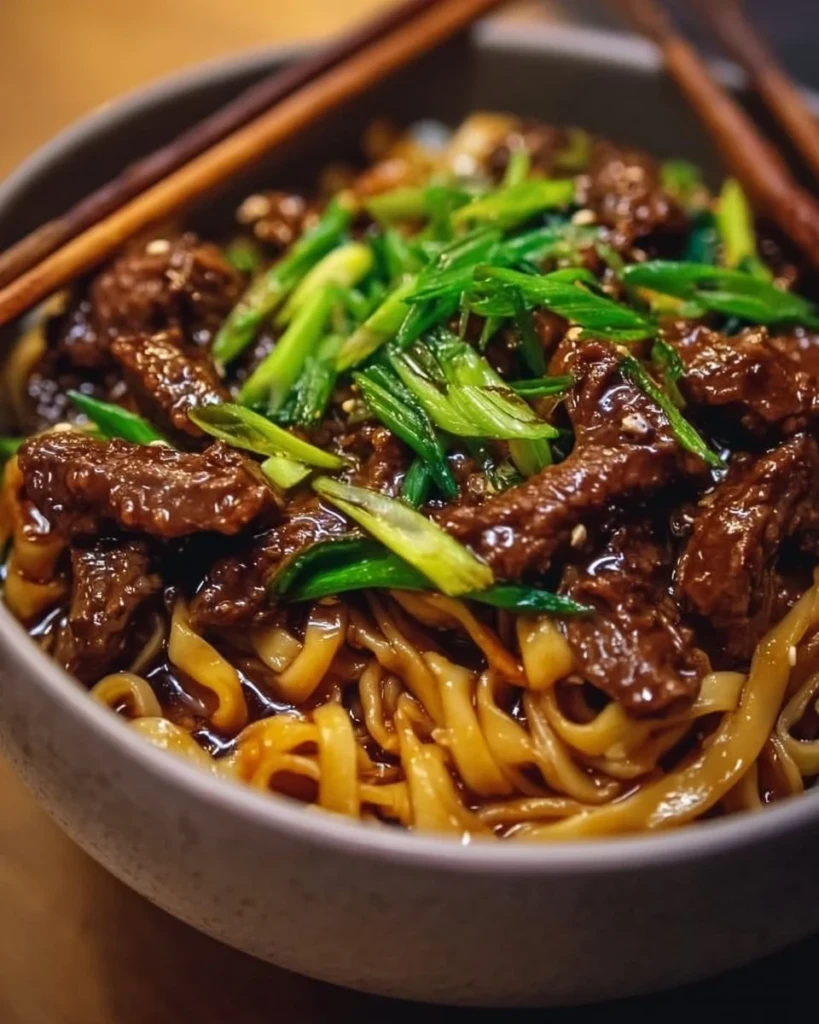 Delicious sticky beef noodles served in a bowl with fresh garnishes