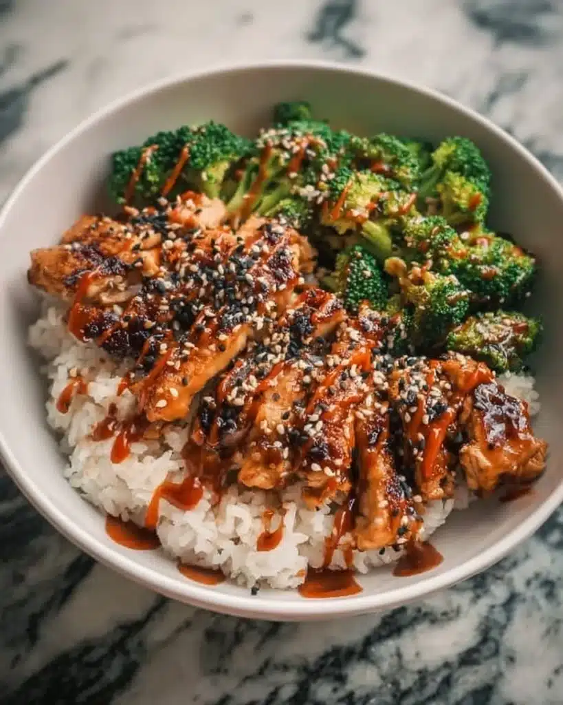 Delicious sticky chicken rice bowls garnished with herbs and vegetables.
