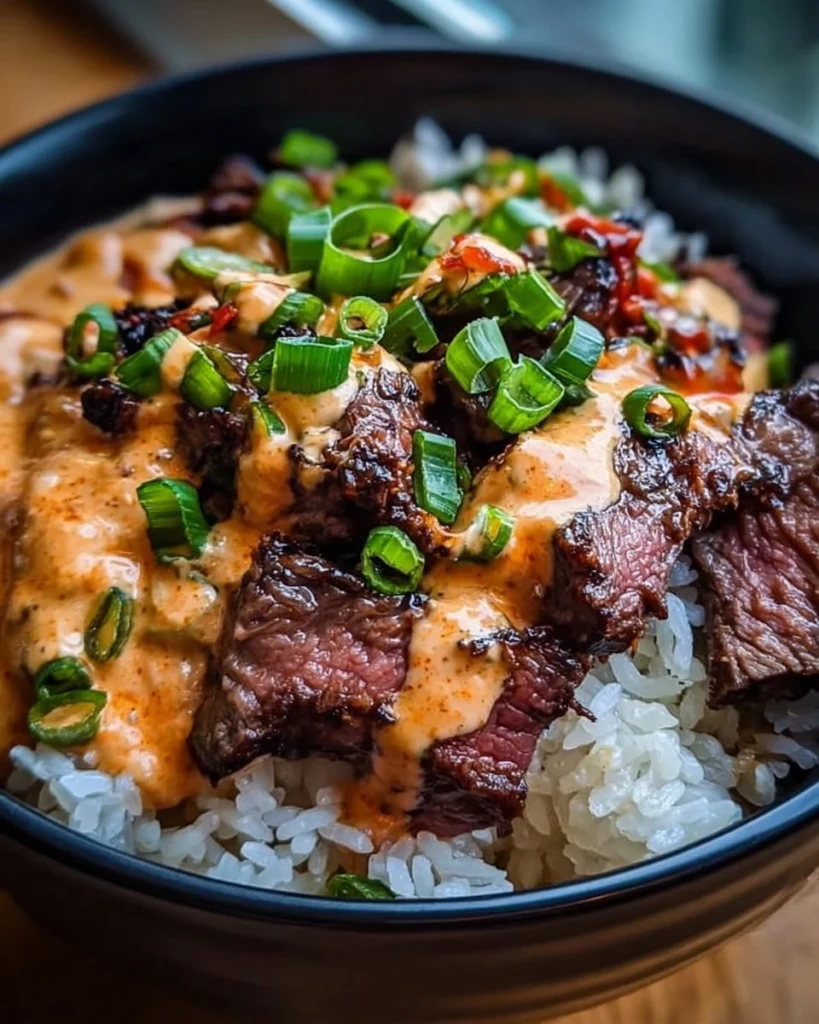 Delicious Korean BBQ Steak rice bowl with spicy cream sauce served on a table.
